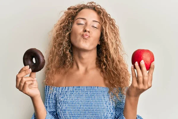 美丽的高加索少女拿着红色的苹果和甜甜圈 看着镜头吹一个吻是可爱和性感的 爱的表达 — 图库照片
