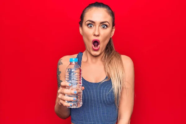 Junge Schöne Blonde Frau Trinkt Flasche Wasser Über Isolierten Roten — Stockfoto
