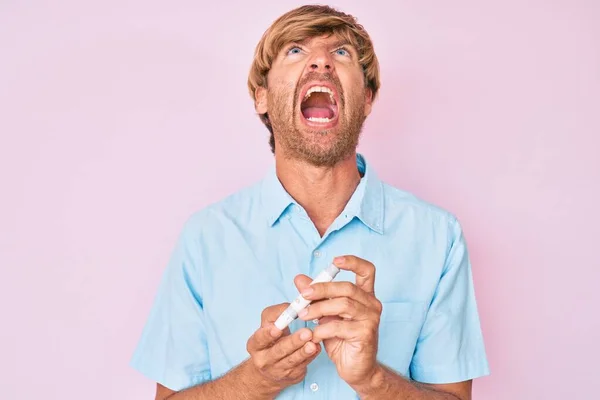 Junger Blonder Mann Mit Glukosemesser Wütend Und Verrückt Schreiend Frustriert — Stockfoto