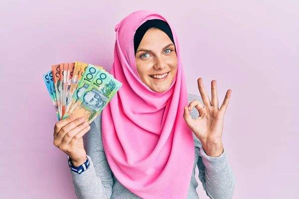 年轻的高加索女人 头戴伊斯兰头巾 手执澳元钞票 手握手拿着手签 友好地做手势 表示出极好的象征 — 图库照片