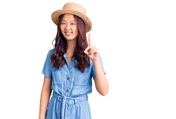 年轻美丽的中国姑娘戴着夏帽 指指点点地提出了一个成功的主意 又兴奋又快乐第一大 — 图库照片