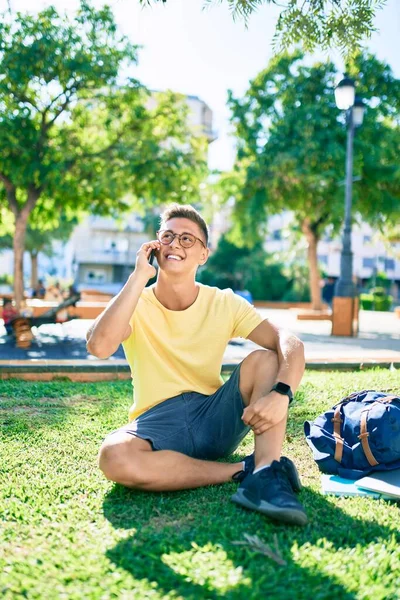 Молодой Латиноамериканец Улыбается Счастливо Используя Смартфон Сидя Траве Университетском Городке — стоковое фото