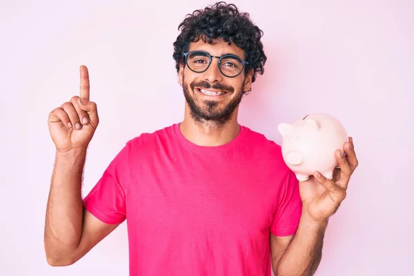 Bonito Jovem Com Cabelo Encaracolado Urso Segurando Porquinho Banco Surpreso — Fotografia de Stock