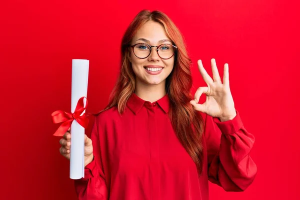 持有研究生文凭的红头发年轻女子手握手签 笑容满面 摆出一副友善的姿态 是个很好的象征 — 图库照片