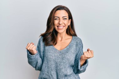 Kış süveteri giyen genç esmer kadın kolları havada ve gözleri kapalı zaferi kutlarken heyecanla bekliyor. Kazanan konsept. 