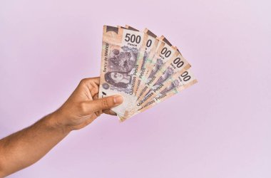 İspanyol eli 500 Meksika Pezosu 'nu soyutlanmış pembe arka planda tutuyor..