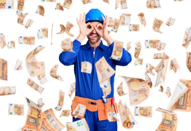 Genç, yakışıklı bir adam işçi üniforması giyiyor ve şapkası takıyor. Dürbün gibi jest yapıyor. Dürbün dilini çıkarıyor, gözler parmaklarından bakıyor. çılgın ifade.