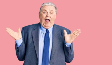 İş ceketi giyen yaşlı gri saçlı adam çılgın ve başarıyı kollarını kaldırıp heyecanla haykırarak kutluyor. Kazanan konsept 