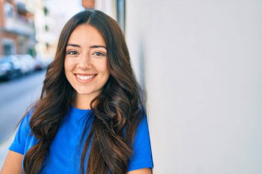 Genç İspanyol kadın gülümsüyor mutlu bir şekilde şehrin duvarına yaslanıyor..