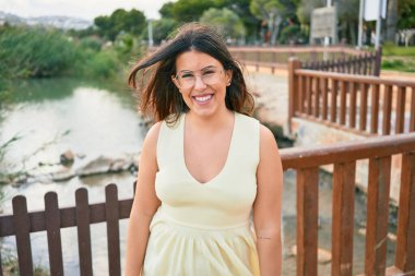 Mutlu gülümseyen genç ve güzel bir kadın. Yüzünde gülümsemeyle kasaba caddesinde yürürken.