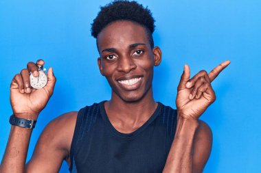 Kronometre tutan genç Afro-Amerikalı adam gülümsüyor. 