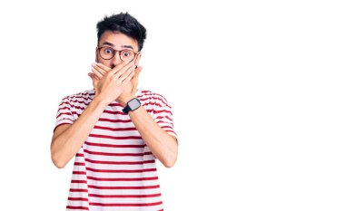 Gündelik kıyafetler giyen genç İspanyol adam yanlışlıkla elleri ile ağzını kapatırken şok oldu. gizli kavram. 