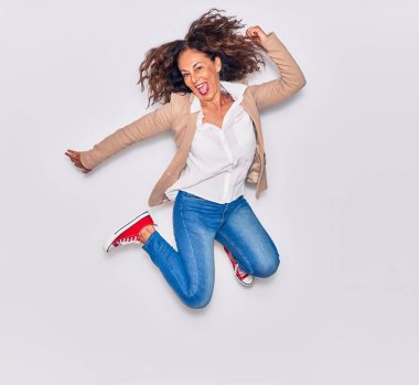 Zarif kıyafetler giyen genç ve güzel İspanyol iş kadını bunu ağzıyla kutluyor. İzole edilmiş beyaz arkaplan üzerinden atlama