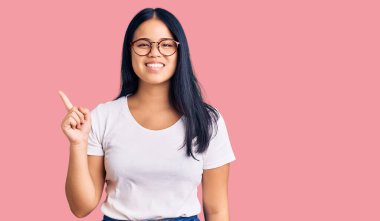 Genç, güzel Asyalı bir kız. Günlük kıyafetler ve gözlük takıyor. Yüzünde kocaman bir gülümseme var.. 