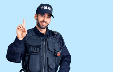 Sakallı, polis üniforması giyen genç yakışıklı bir numaralı parmağını gösterip onu gösterirken kendinden emin ve mutlu bir şekilde gülümsüyor.. 