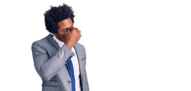 Afro saçlı, iş ceketi giyen, burnu ve gözleri ovuşturmaktan yorgun, yorgun ve başı ağrıyan yakışıklı Afro-Amerikan bir adam. Stres ve hüsran kavramı. 