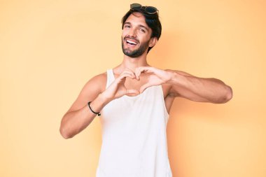 Yaz bakışı takan yakışıklı İspanyol bir adam ve aşkta gülümseyen bir güneş gözlüğü. Elleriyle kalp sembolü yapıyor. romantik kavram. 