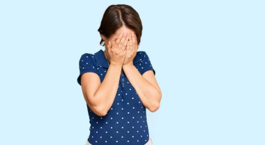 Kısa saçlı, esmer, sıradan kıyafetler giyen, suratını ellerle örten ve ağlayan genç bir kadın. depresyon kavramı. 