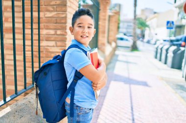 Sevimli öğrenci gülümsüyor. Şehrin caddesinde kitap tutarken mutlu..