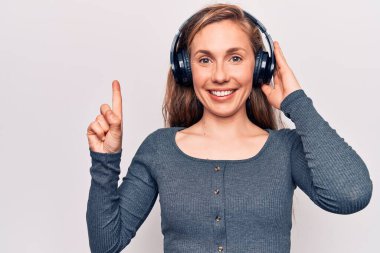 Müzik dinleyen, kulaklık takan genç, güzel, sarışın bir kadın bir fikirle gülümseyen ya da soru işareti yapan mutlu yüzlü, bir numara. 