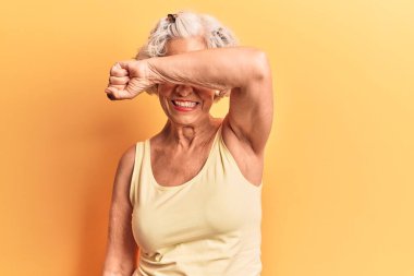 Son sınıftaki gri saçlı kadın, günlük kıyafetler giyiyor, gözleri kollarıyla örtüyor, neşeli ve komik gülümsüyor. kör kavram. 