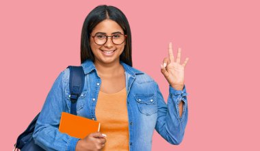 Sırt çantası takan ve elinde kitaplarla gülümseyen genç Latin kız el ve parmaklarıyla 