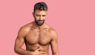 İspanyol asıllı genç adam mayo giyiyor ve elleri karnında çünkü hazımsızlık, acı verici bir hastalık kendini iyi hissetmiyor. Ağrı kavramı. 