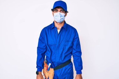 Kıvırcık saçlı, ayılı, tamirci üniforması giyen ve mutlu ve havalı bir gülümsemesi olan yakışıklı bir genç adam. şanslı kişi. 