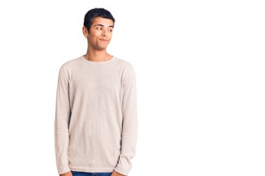 Genç Afrikalı Amerikalı, günlük kıyafetler giymiş, gülümseyen, yan tarafa bakan ve düşünen.. 