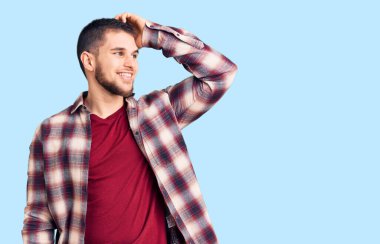 Genç, yakışıklı, rahat gömlekler giyen, gülümseyen, kendine güvenen, el hareketleriyle saçlara dokunan, çekici ve modaya uygun poz veren bir adam. 