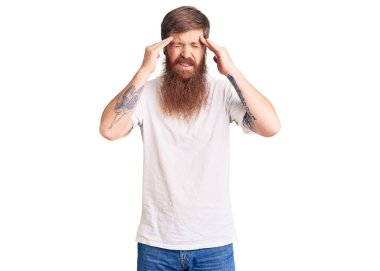Yakışıklı, kızıl saçlı, uzun sakallı beyaz tişörtlü, başı ağrıyan bir adam. migren ağrısı. 