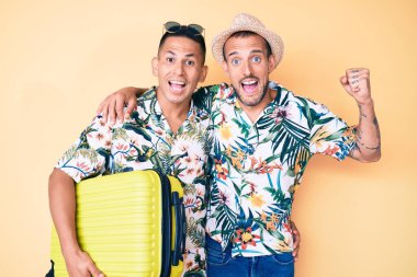 Genç eşcinsel iki adam ellerinde bavullarıyla yaz tatiline çıkıyorlar gururla bağırıyorlar, zaferi kutluyorlar ve kollarını kaldırarak çok heyecanlılar. 