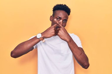 Genç Afro-Amerikalı, günlük kıyafetler giymiş, reddedilmiş yüz ifadesi. Eksi işareti yapıyor. 