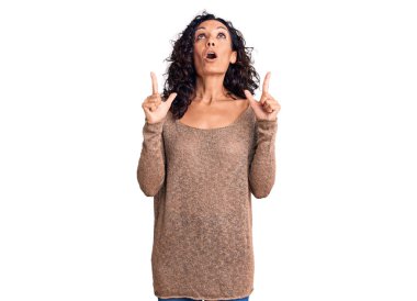 Orta yaşlı, güzel bir kadın gündelik süveter giyip şaşkın şaşkın yukarı bakıyor, parmaklarıyla işaret ediyor ve kollarını kaldırıyordu.. 