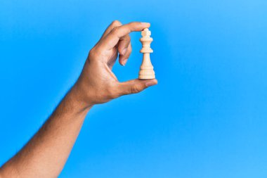 Mavi arka planda satranç taşını tutan İspanyol bir adam..