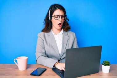 Ofiste çalışan genç ve güzel esmer kadın operatör kulaklığı takıyor. Korkuyor ve hayrete düşüyor. 