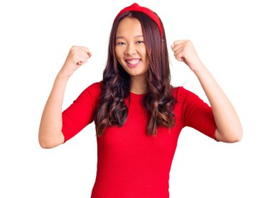 Genç ve güzel Çinli kız gündelik kıyafetler giyiyor ve Diadem haykırıyor gururla, zaferi kutluyor ve başarıyı kollarını kaldırarak kutluyor. 