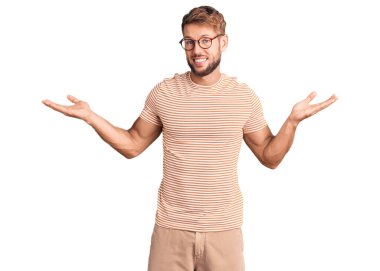 Gündelik giysiler ve gözlük takan genç beyaz bir adam gülümseyerek avuçlarını açıyor, sunuyor ve reklam karşılaştırması yapıyor ve dengeyi sağlıyor. 