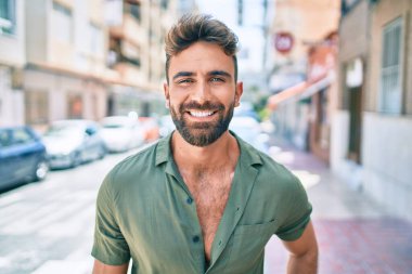Genç İspanyol adam gülümseyerek şehirde mutlu bir şekilde yürüyor.