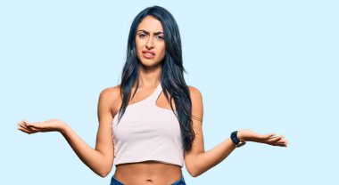 Gündelik kıyafetler giyen, kolları açık ve kafası karışmış, hiçbir fikri olmayan güzel İspanyol bir kadın.. 