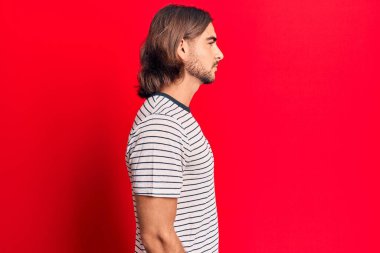 Sıradan kıyafetler giyen genç yakışıklı bir adam, rahat bir görünüm takınıyor kendine güvenen bir gülümsemeyle doğal bir yüz ifadesi takınıyor.. 