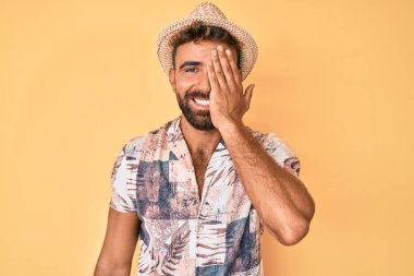 Yaz şapkası takan genç İspanyol bir adam bir gözünü eliyle kapatıyor, yüzünde kendine güvenen bir gülümseme ve şaşırtıcı bir duygu var.. 