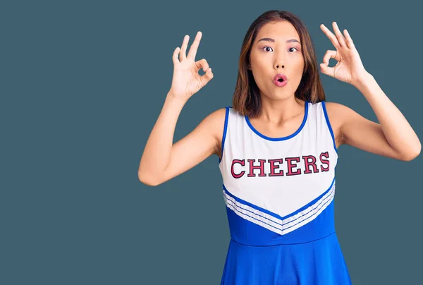 身穿啦啦队队长制服的年轻漂亮的中国姑娘看上去很惊讶 也很震惊用手指做了个认可的标志 疯狂的表达 — 图库照片