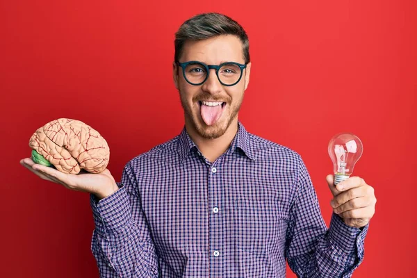 Handsome Caucasian Man Holding Brain Lightbulb Inspiration Idea Sticking Tongue — Stock Photo, Image