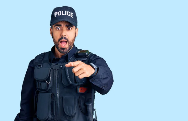 Young hispanic man wearing police uniform pointing displeased and frustrated to the camera, angry and furious with you