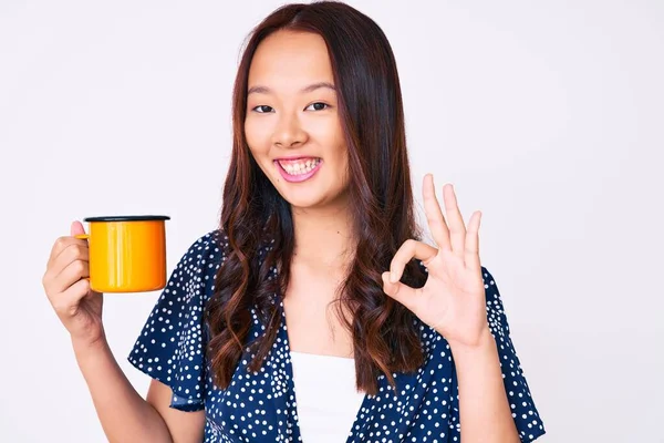 年轻美丽的中国女孩手握咖啡 手握手签 微笑友好的手势 是极好的象征 — 图库照片