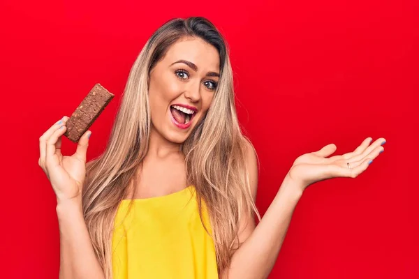 Jovem Mulher Loira Bonita Comendo Barra Proteína Chocolate Sobre Fundo — Fotografia de Stock