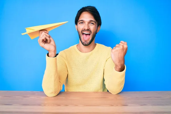 Hombre Hispano Guapo Sosteniendo Avión Papel Gritando Orgulloso Celebrando Victoria —  Fotos de Stock