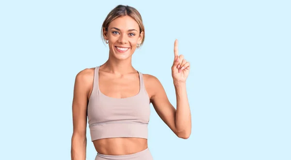 Beautiful Caucasian Woman Wearing Sportswear Showing Pointing Finger Number One — Stock Photo, Image