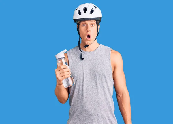 Młody Przystojny Mężczyzna Noszenie Kask Rowerowy Trzymając Butelkę Wody Przestraszony — Zdjęcie stockowe